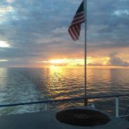 sunset on the water with flag pole